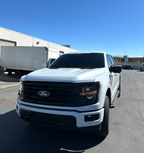 White Ford truck parked on a clear day with a blue sky.