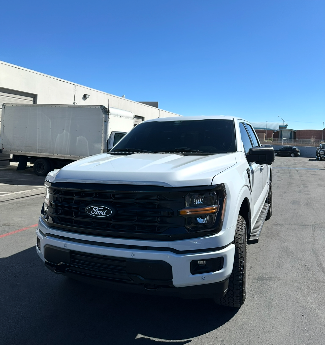 White Ford truck parked on a clear day with a blue sky.