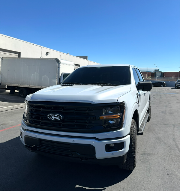 White Ford truck parked on a clear day with a blue sky.