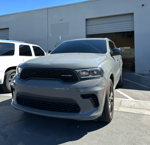 White SUV parked in front of a building with a clear blue sky.