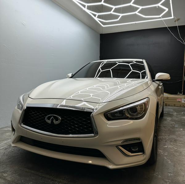 White Infiniti car in a showroom with geometric ceiling design