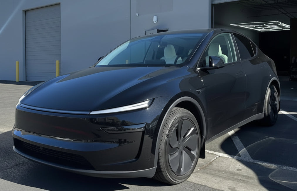 Black electric vehicle parked in front of a building with a clear blue sky.