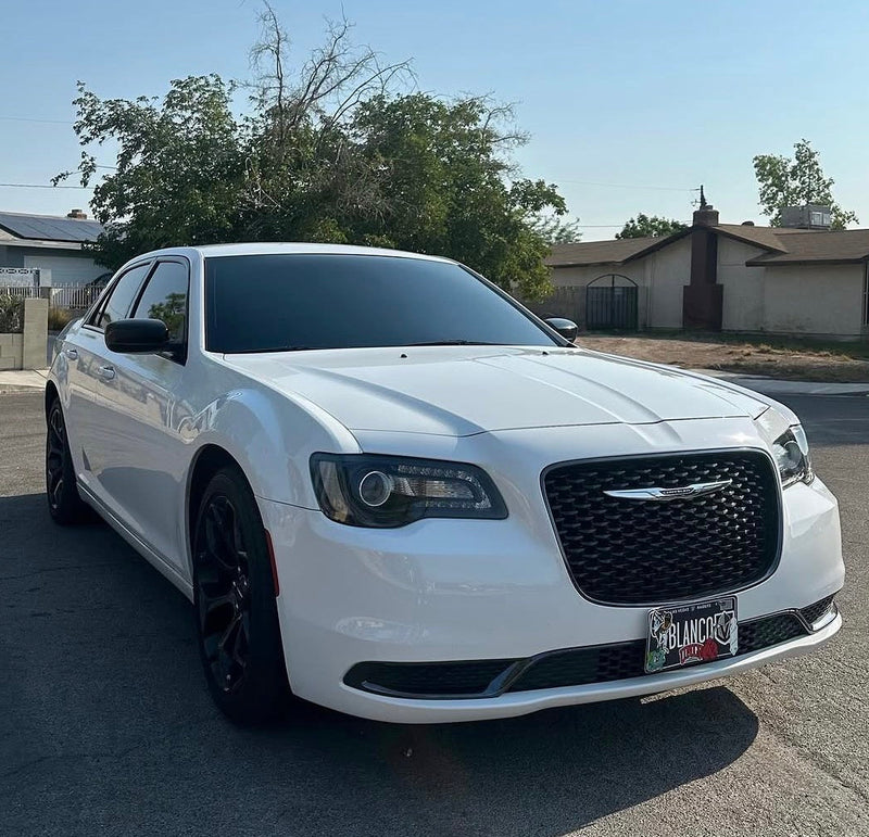 White Chrysler car parked on a street with houses and trees in the background