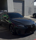 Black Lexus car parked in a parking lot with a building in the background