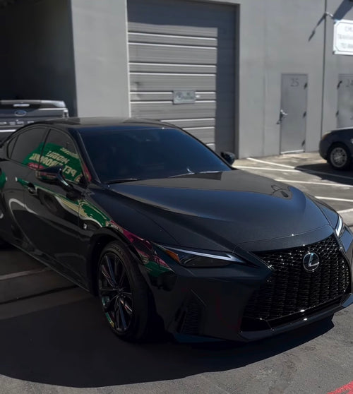 Black Lexus car parked in a parking lot with a building in the background